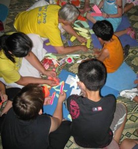  ילדים והוריהם מכינים פרחי לוטוס מנייר צבעוני ושומעים על הפאלון דאפא